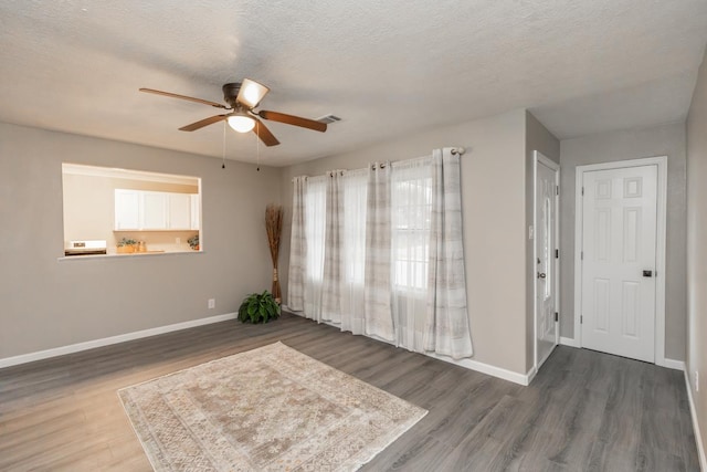 unfurnished room with visible vents, a textured ceiling, baseboards, and dark wood-type flooring