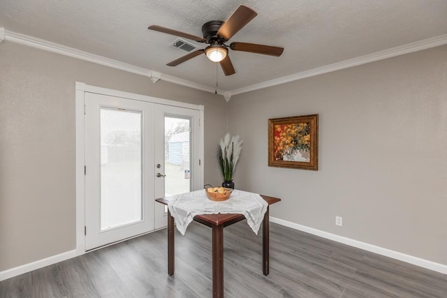 dining space featuring baseboards, visible vents, dark wood-style flooring, crown molding, and french doors