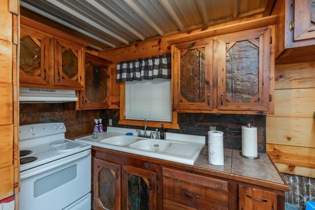 3075 Shivers St, Vidor, TX 77662 - kitchen with white range with electric stovetop, under cabinet range hood, a sink, brown cabinets, and light countertops
