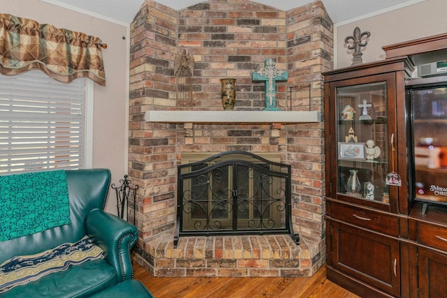 living room with hardwood / wood-style floors, ornamental molding, a fireplace, and vaulted ceiling