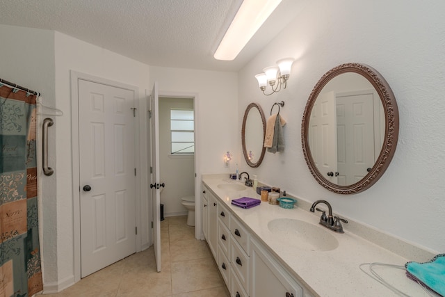 bathroom with vanity, tile patterned floors, a textured ceiling, and toilet