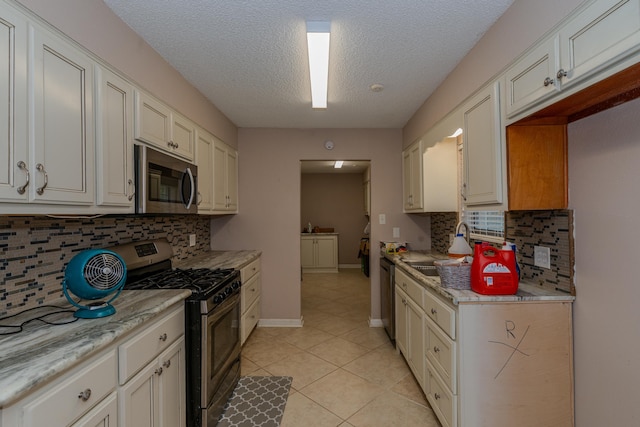 kitchen featuring white cabinets, stainless steel appliances, light stone counters, and tasteful backsplash