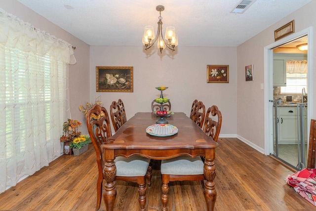 dining room featuring a notable chandelier, wood-type flooring, and a textured ceiling