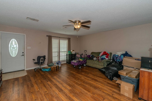 interior space with a textured ceiling, ceiling fan, and dark wood-type flooring