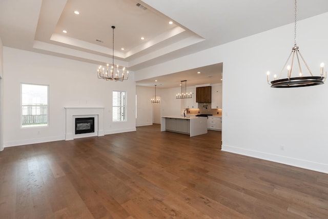 3570 Lily Ln, Beaumont, TX 77713 - unfurnished living room with a chandelier, a tray ceiling, plenty of natural light, baseboards, and recessed lighting
