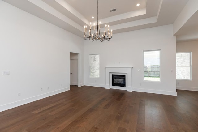 3570 Lily Ln, Beaumont, TX 77713 - unfurnished living room with a chandelier, a tray ceiling, dark wood-type flooring, a glass covered fireplace, and baseboards