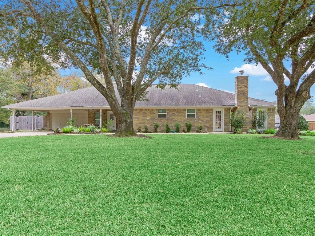 12955 Mintwood Dr, Beaumont, TX 77706 - single story home featuring a chimney, an attached carport, concrete driveway, a front yard, and an attached garage