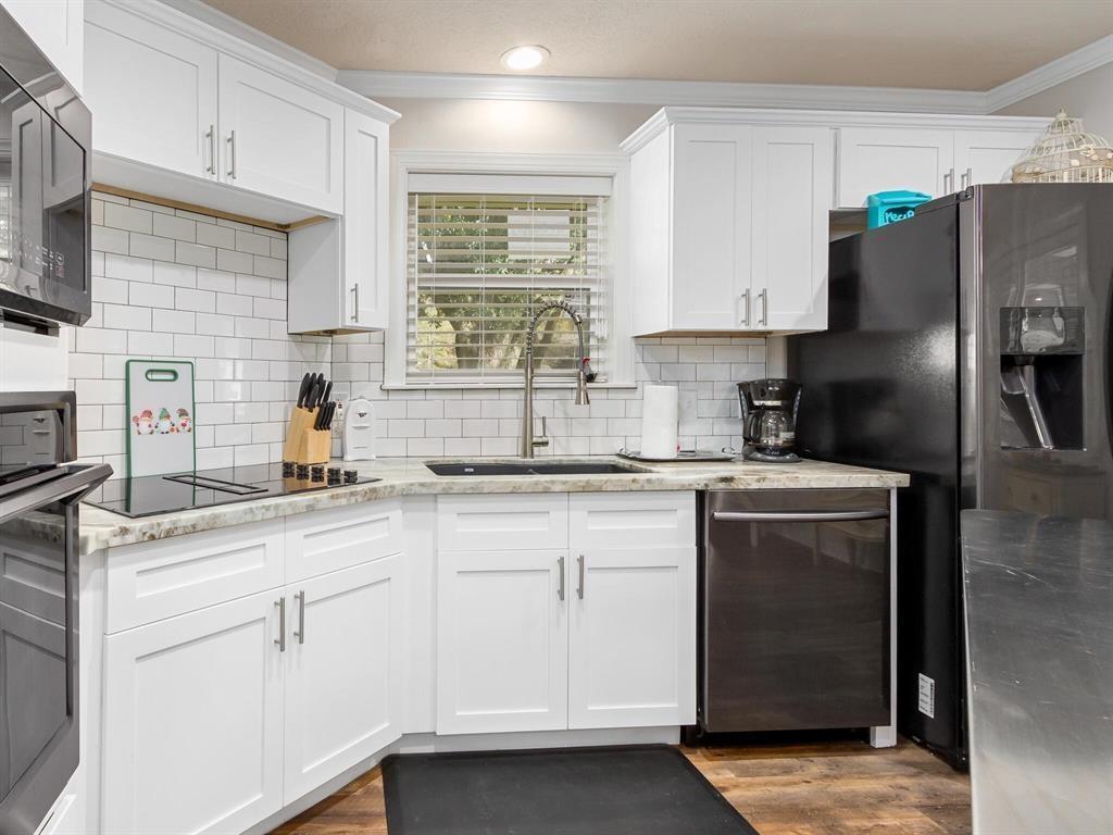 12955 Mintwood Dr, Beaumont, TX 77706 - kitchen with a sink, black appliances, crown molding, white cabinets, and light stone counters