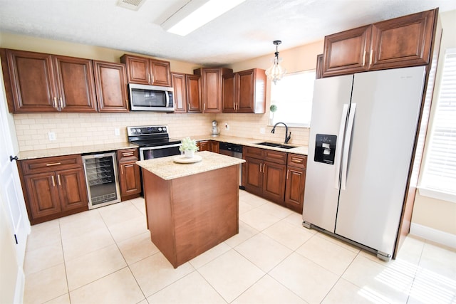 kitchen with sink, decorative light fixtures, a center island, appliances with stainless steel finishes, and beverage cooler