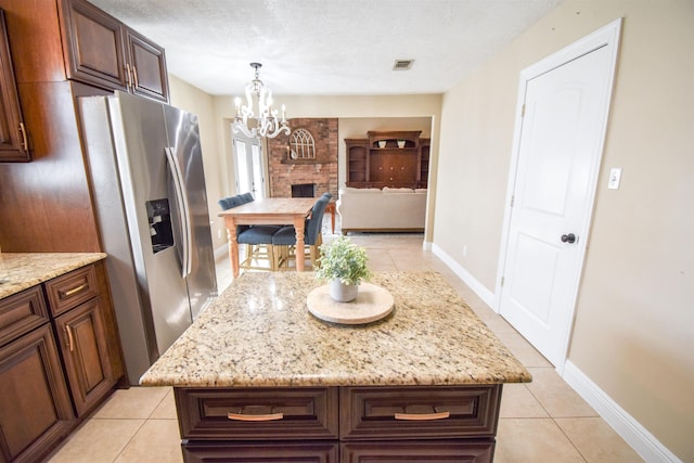 kitchen with an inviting chandelier, a center island, hanging light fixtures, a textured ceiling, and stainless steel fridge