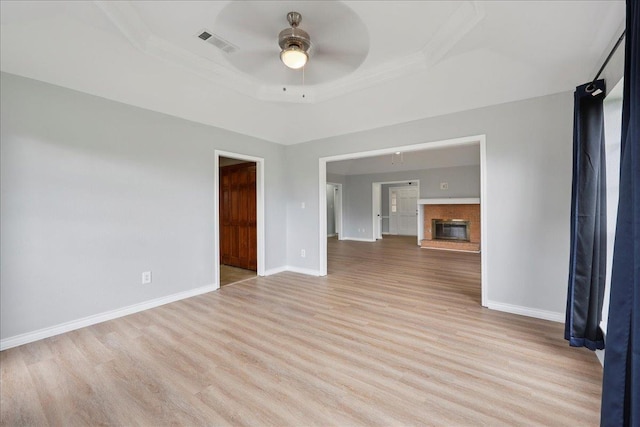 1120 Meadowvale Dr, Beaumont, TX 77706 - unfurnished living room with a ceiling fan, ornamental molding, light wood finished floors, a raised ceiling, and a glass covered fireplace