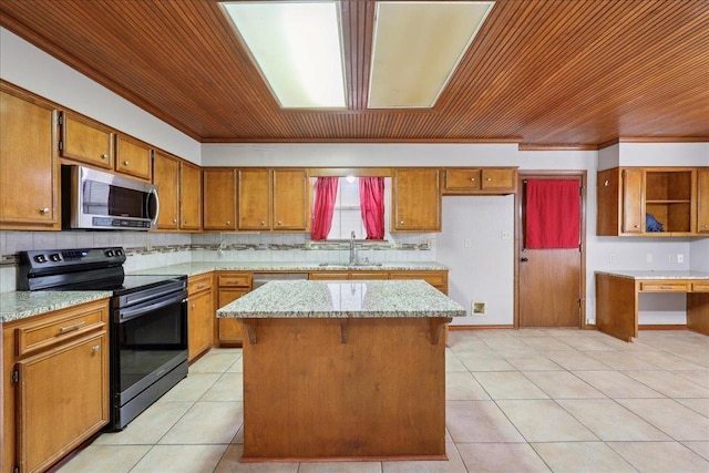 1120 Meadowvale Dr, Beaumont, TX 77706 - kitchen featuring black range with electric stovetop, stainless steel microwave, brown cabinetry, a center island, and light tile patterned flooring