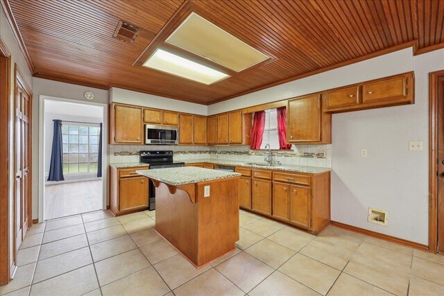 1120 Meadowvale Dr, Beaumont, TX 77706 - kitchen featuring stainless steel microwave, electric range oven, wood ceiling, brown cabinetry, and plenty of natural light