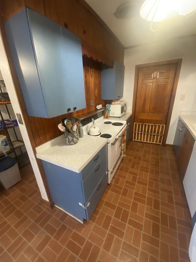 kitchen with wooden walls, white appliances, and blue cabinets