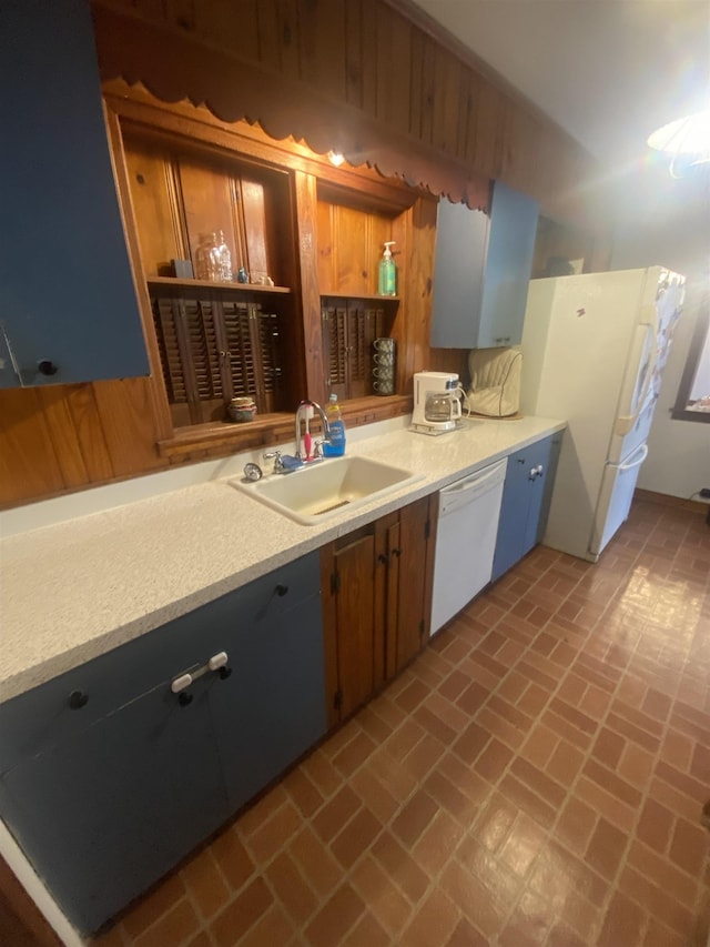 kitchen with white appliances, wood walls, and sink