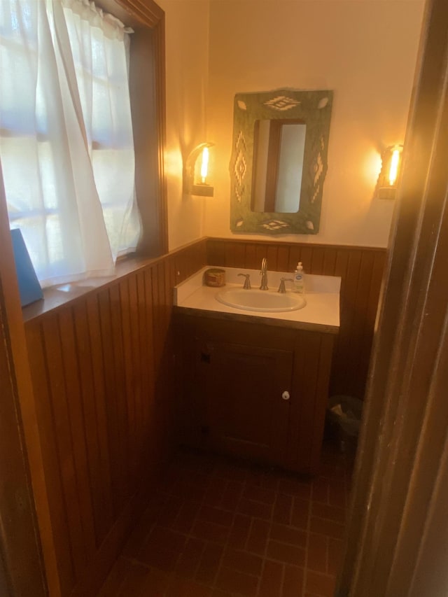 bathroom featuring tile patterned flooring, vanity, a healthy amount of sunlight, and wood walls