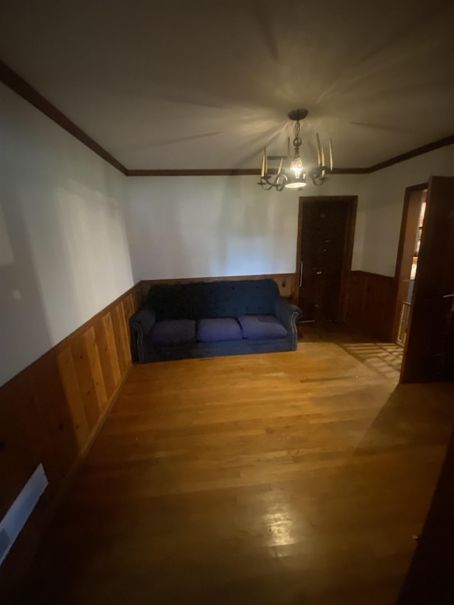 unfurnished living room with a chandelier, wood-type flooring, and ornamental molding