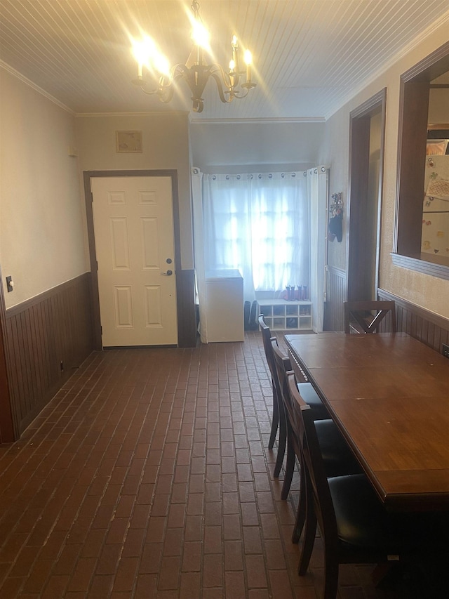 dining area featuring a notable chandelier, crown molding, and wooden walls