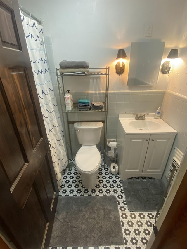 bathroom featuring curtained shower, vanity, tile walls, and toilet