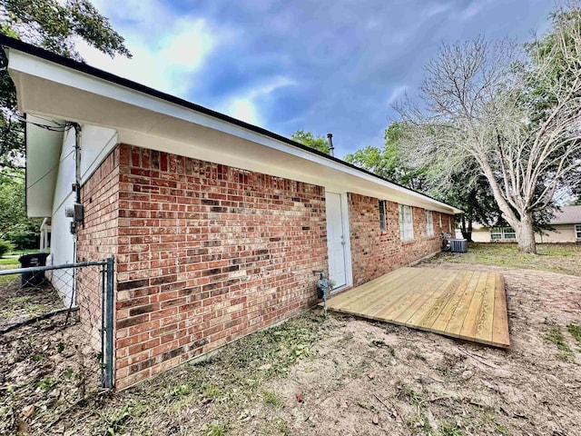 view of side of home with central AC unit and a wooden deck