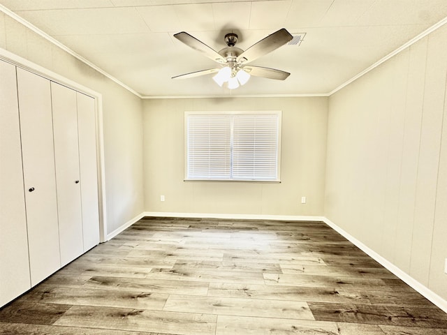 unfurnished bedroom featuring hardwood / wood-style flooring, ceiling fan, and crown molding