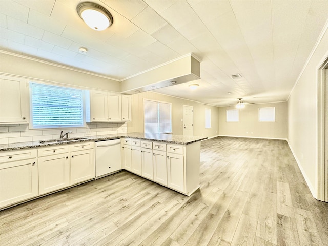 kitchen with dark stone counters, white dishwasher, sink, tasteful backsplash, and kitchen peninsula