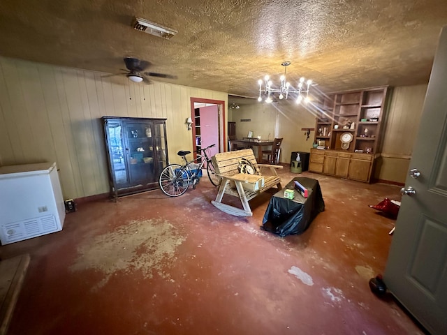 interior space with ceiling fan with notable chandelier, concrete flooring, and a textured ceiling