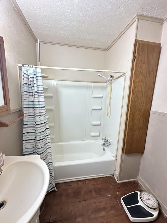 bathroom featuring a textured ceiling, wood-type flooring, shower / bath combo with shower curtain, and sink