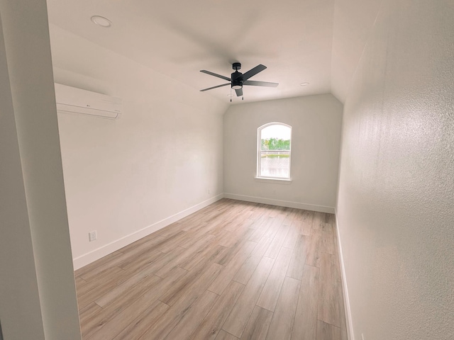 spare room with a wall mounted air conditioner, light hardwood / wood-style floors, vaulted ceiling, and ceiling fan