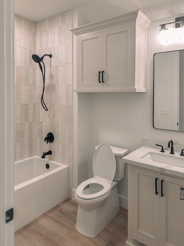 full bathroom with vanity, tiled shower / bath combo, hardwood / wood-style flooring, and toilet