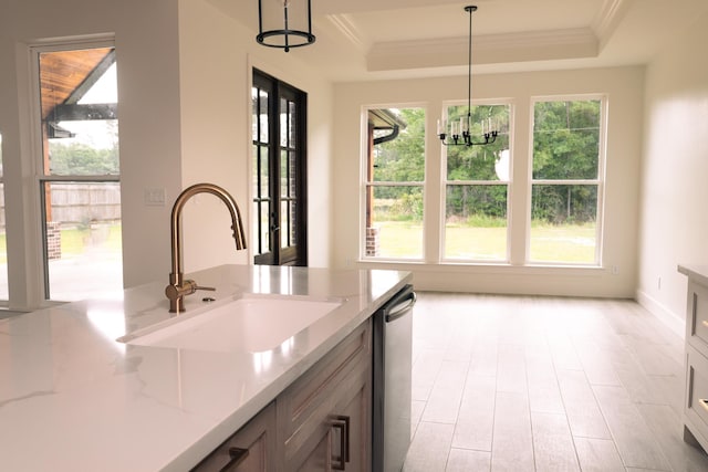 kitchen featuring pendant lighting, light stone counters, a raised ceiling, and sink