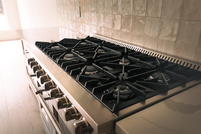 details with stovetop, decorative backsplash, and high end stainless steel range