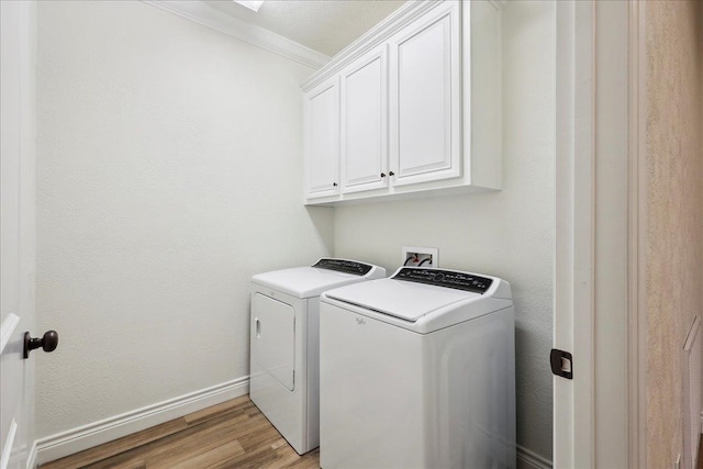 clothes washing area with crown molding, baseboards, washing machine and dryer, light wood-style flooring, and cabinet space