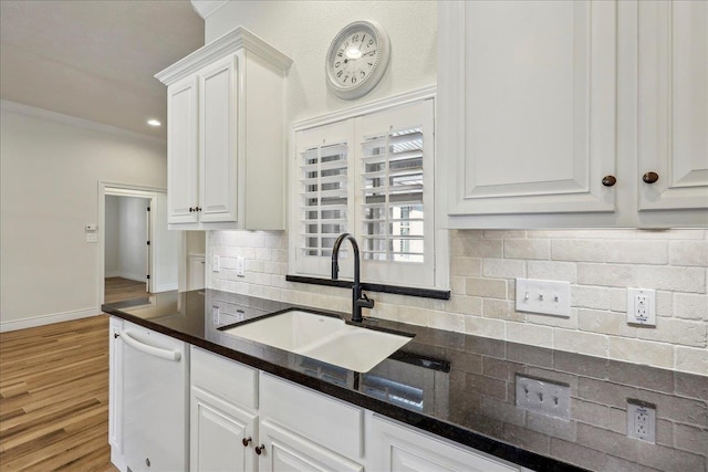 kitchen with ornamental molding, a sink, tasteful backsplash, white cabinetry, and dishwasher