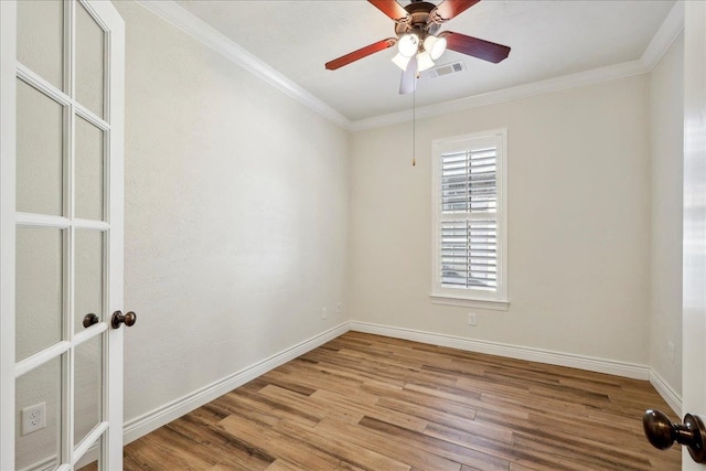 unfurnished room featuring crown molding, wood finished floors, visible vents, and baseboards