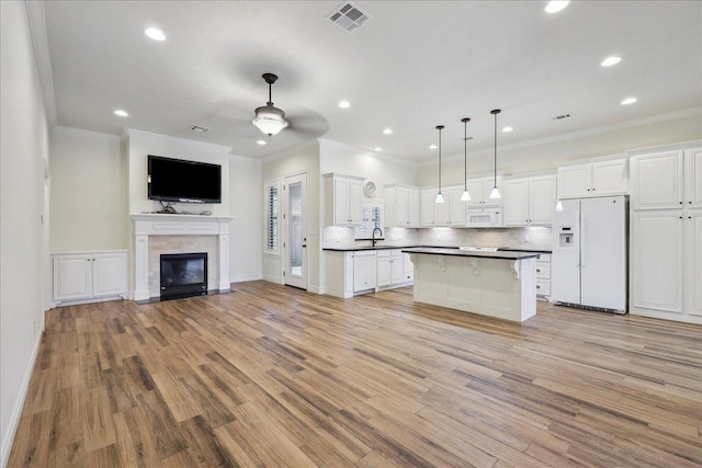 kitchen with visible vents, a sink, dark countertops, open floor plan, and white appliances