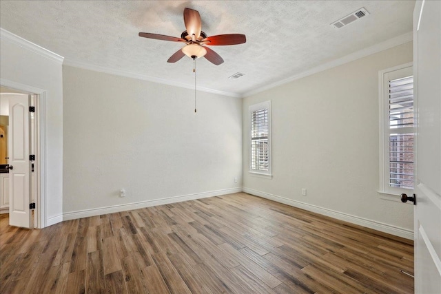 unfurnished room with visible vents, ornamental molding, a textured ceiling, and wood finished floors