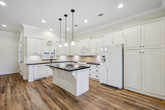 kitchen with dark countertops, tasteful backsplash, white appliances, white cabinetry, and a sink