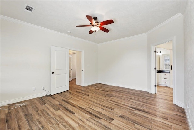 interior space featuring a ceiling fan, baseboards, visible vents, ornamental molding, and light wood-style floors