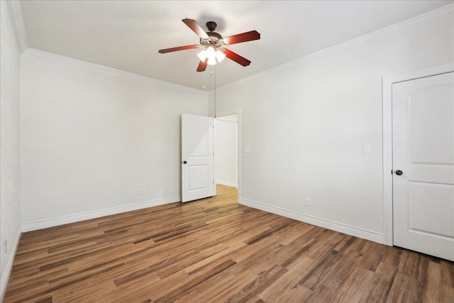 empty room with ceiling fan, baseboards, wood finished floors, and ornamental molding