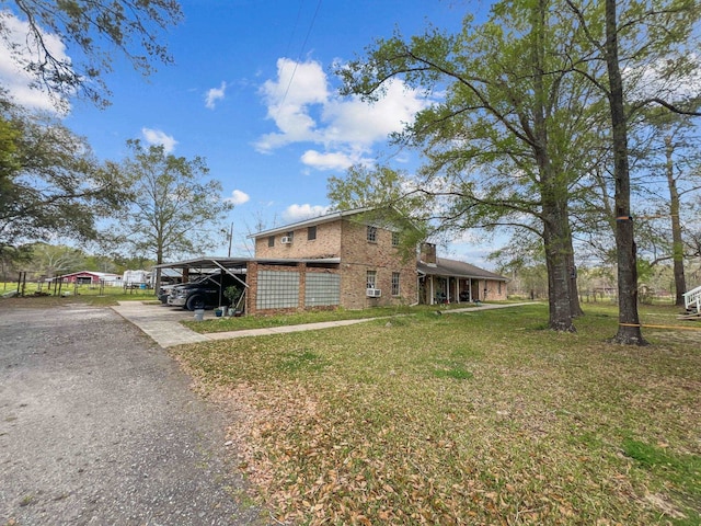 view of front of house with brick siding, an attached carport, driveway, and a front lawn