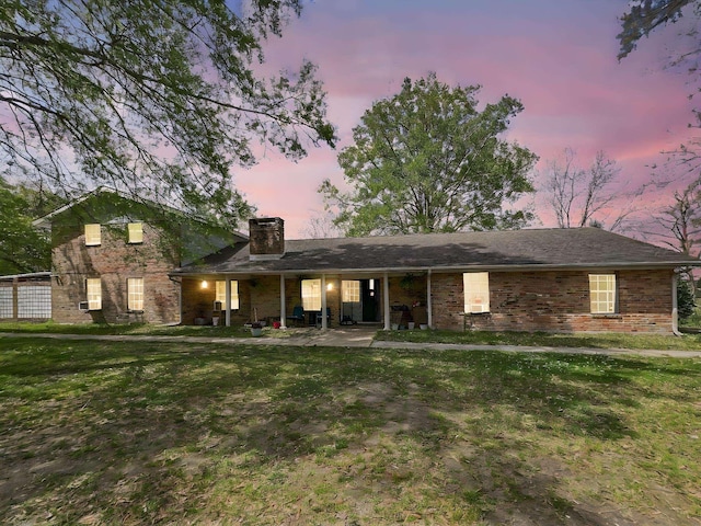view of front of property with brick siding, a chimney, and a front yard