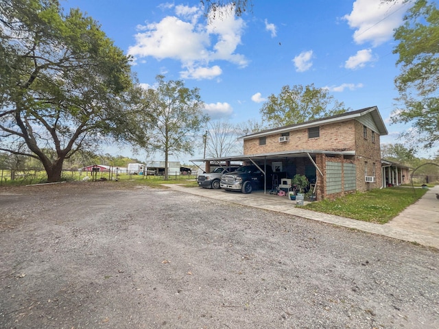 view of front facade featuring brick siding, a carport, and dirt driveway