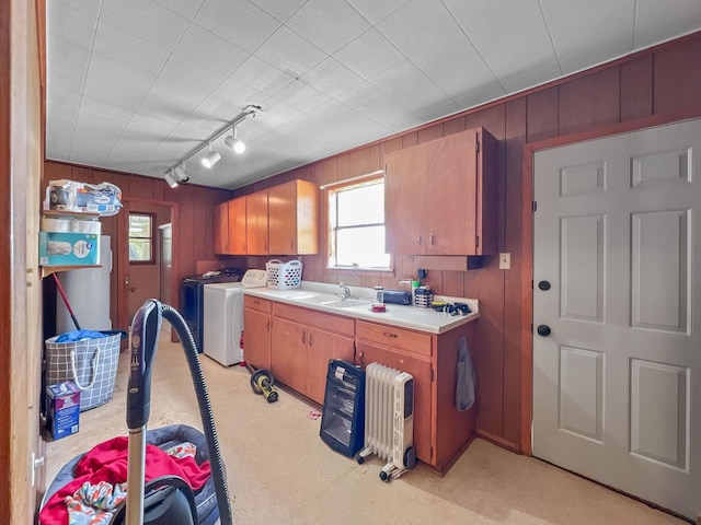 kitchen featuring a sink, wood walls, light countertops, and separate washer and dryer