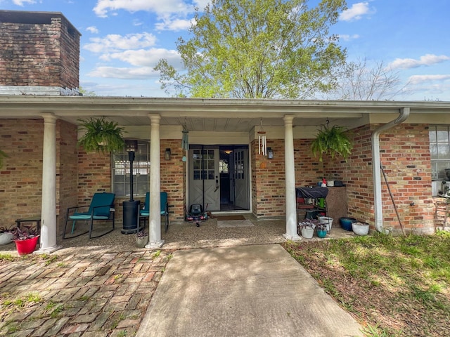property entrance featuring a porch and brick siding