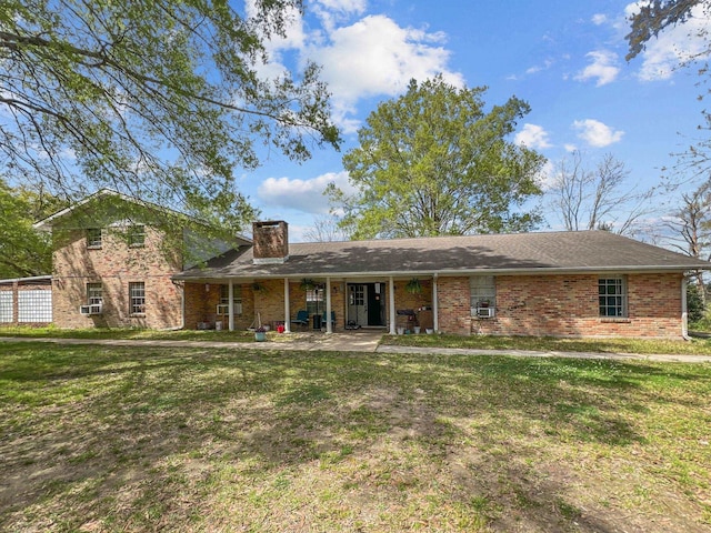 view of front facade with brick siding, a chimney, and a front yard