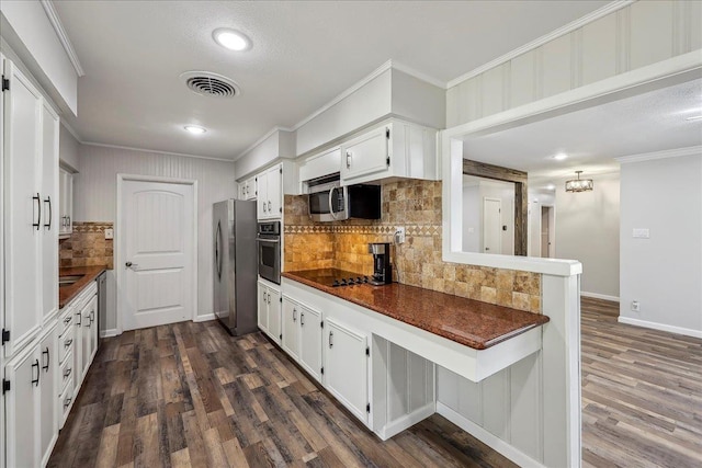 5520 N Circuit Dr, Beaumont, TX 77706 - kitchen featuring dark countertops, visible vents, crown molding, tasteful backsplash, and appliances with stainless steel finishes