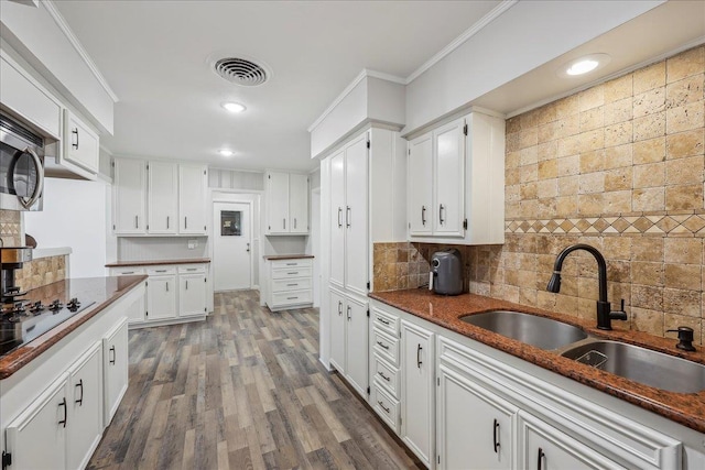 5520 N Circuit Dr, Beaumont, TX 77706 - kitchen featuring black electric cooktop, a sink, tasteful backsplash, visible vents, and white cabinetry