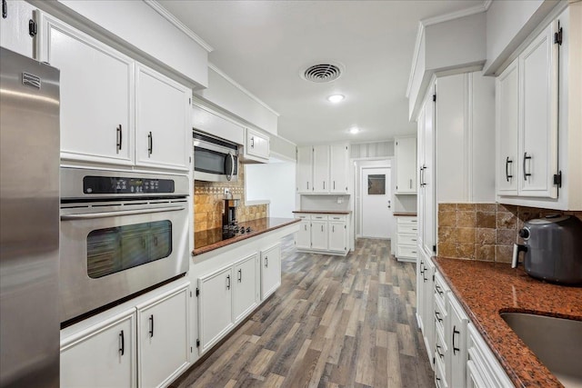 5520 N Circuit Dr, Beaumont, TX 77706 - kitchen featuring white cabinets, stainless steel appliances, tasteful backsplash, wood finished floors, and crown molding