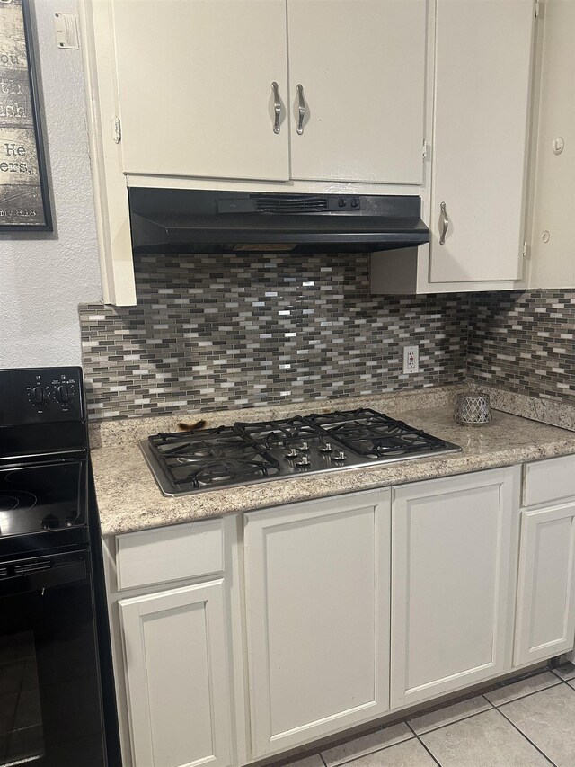 kitchen featuring white cabinetry, gas cooktop, backsplash, black / electric stove, and light tile patterned floors